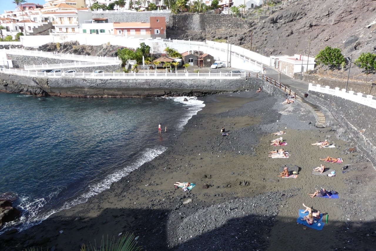 View across the black sand and harbour-front cove at Playa de Puerto Santiago.