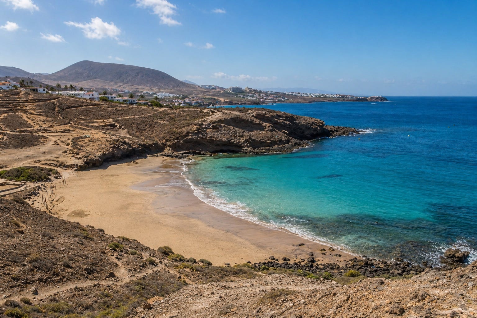View of Playa Diego Hernandez with clear water and rocky coastline.